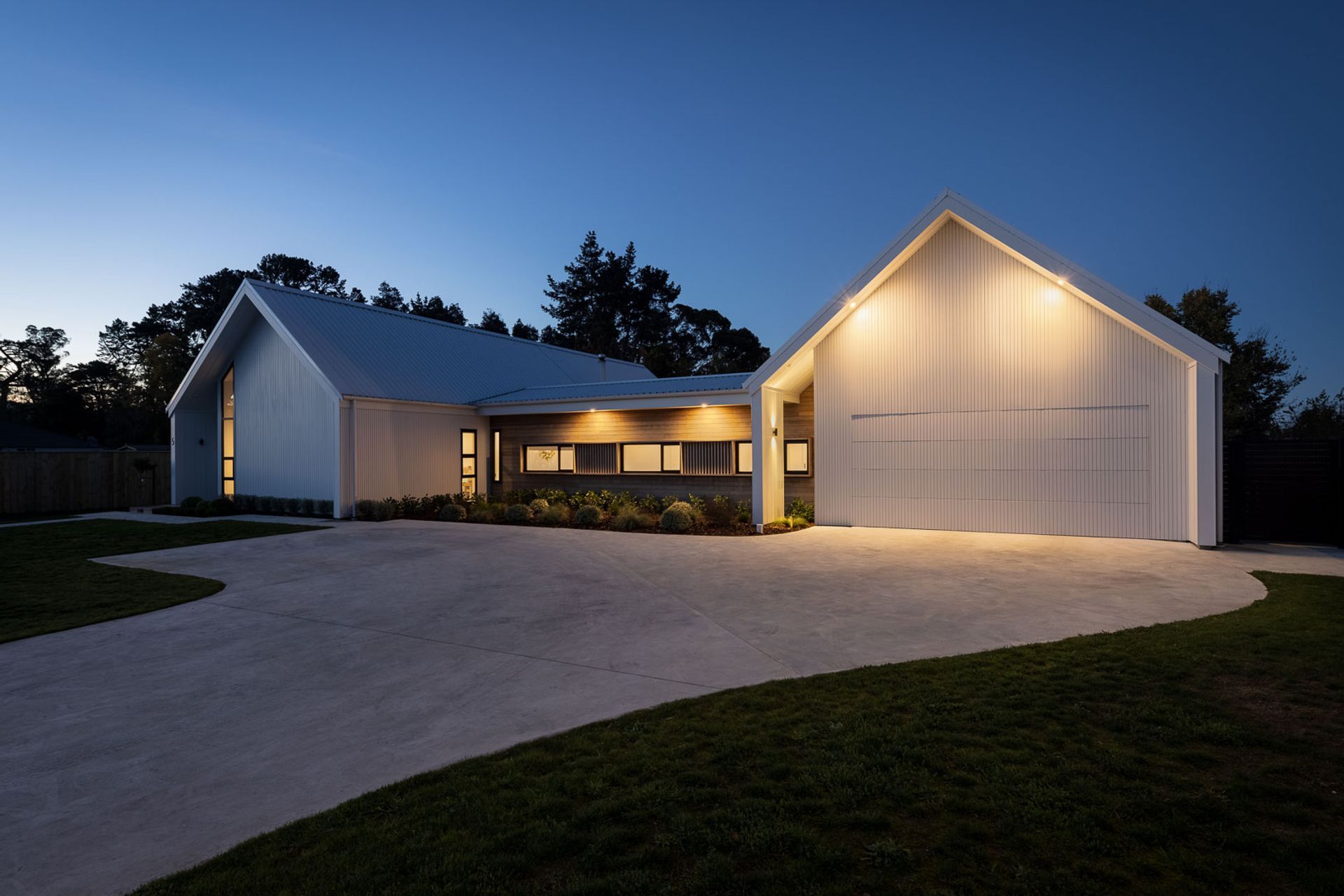 The four gables, generated by the H plan, each present a unique architectural response—flush garage doors, exaggerated verticality and structural portal frames—but are unified through the arresting white exterior colour scheme, wing wall detailing and asy
