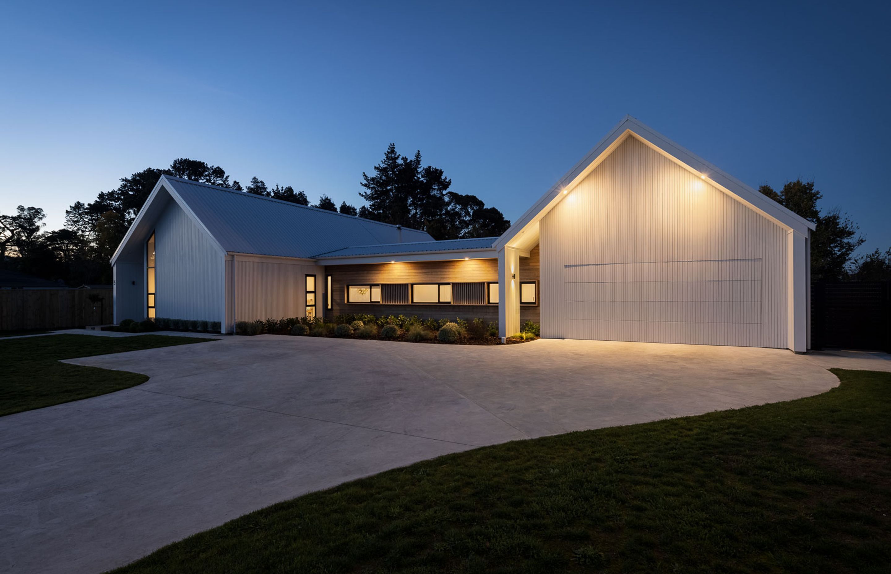 The four gables, generated by the H plan, each present a unique architectural response—flush garage doors, exaggerated verticality and structural portal frames—but are unified through the arresting white exterior colour scheme, wing wall detailing and asy