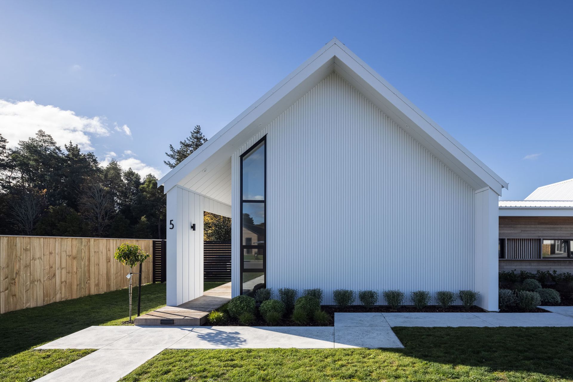 The eastern pavilion houses the living areas and features a set-back front door, again, maintaining the almost unbroken look of the gable end.