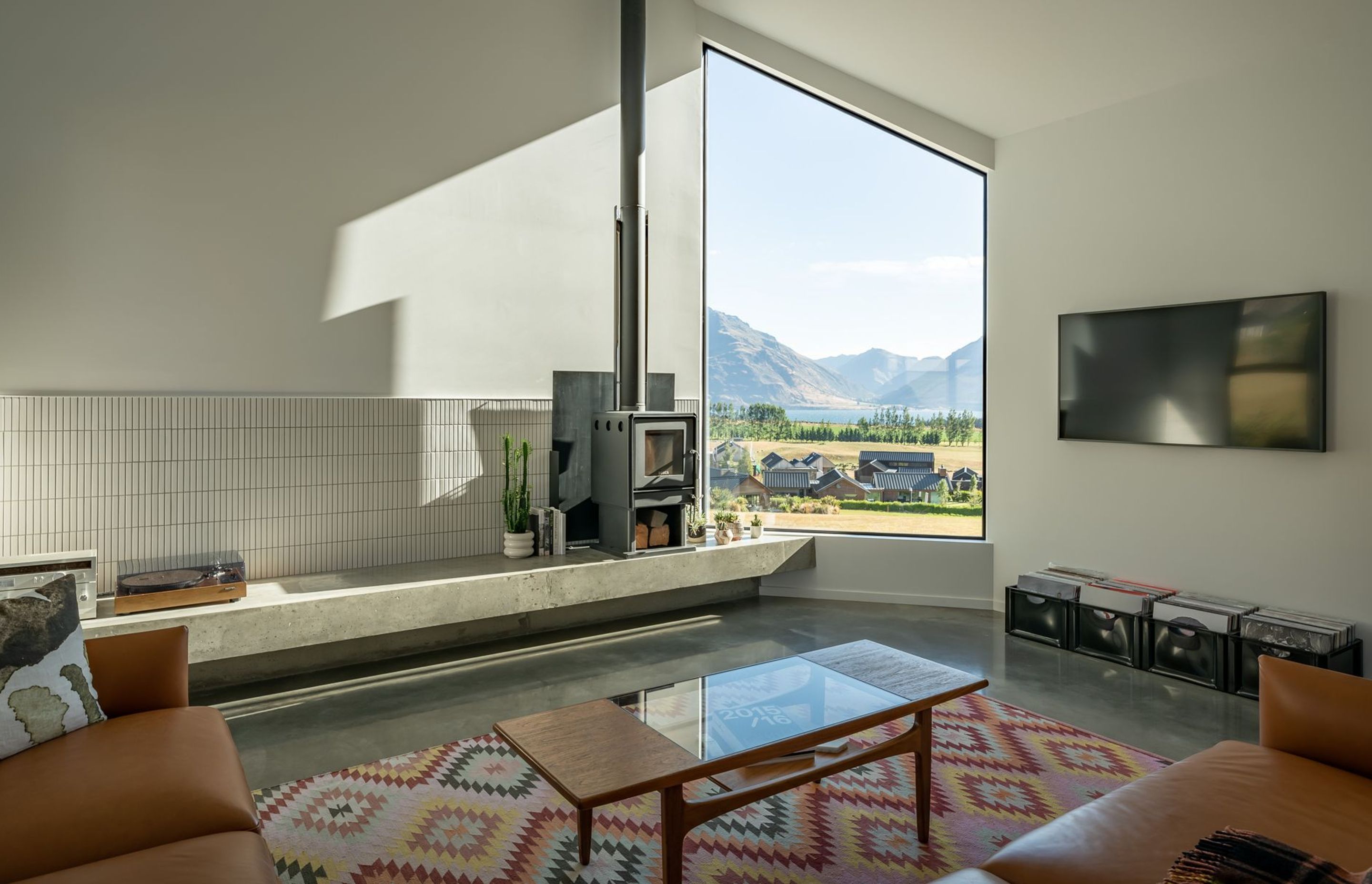 The sunken lounge with woodburner includes a built-in concrete display bench that showcases the homeowner's unique objects.