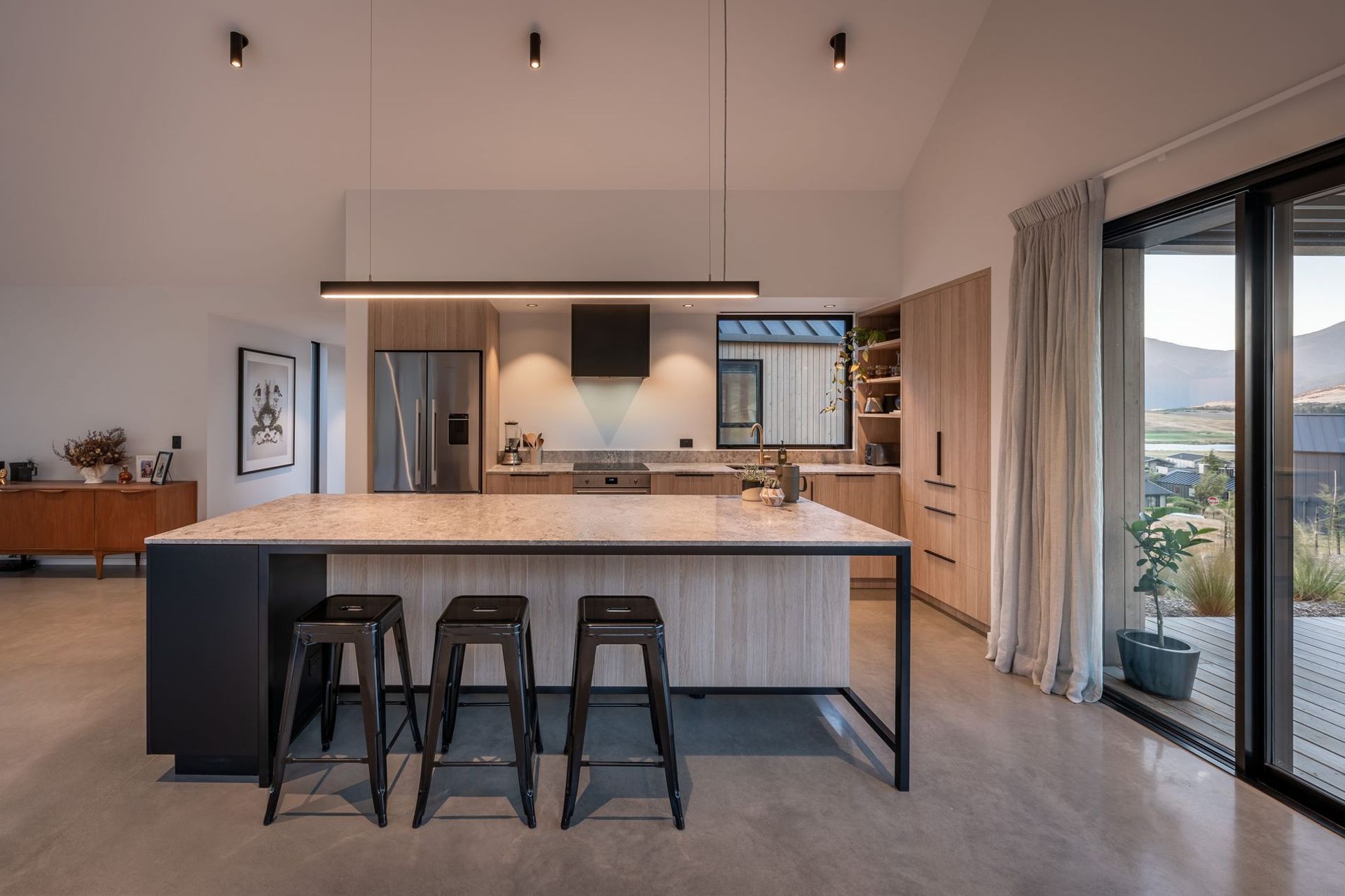 The polished concrete floors throughout the living spaces provide a soothing and neutral anchor for the biophilic materiality throughout.