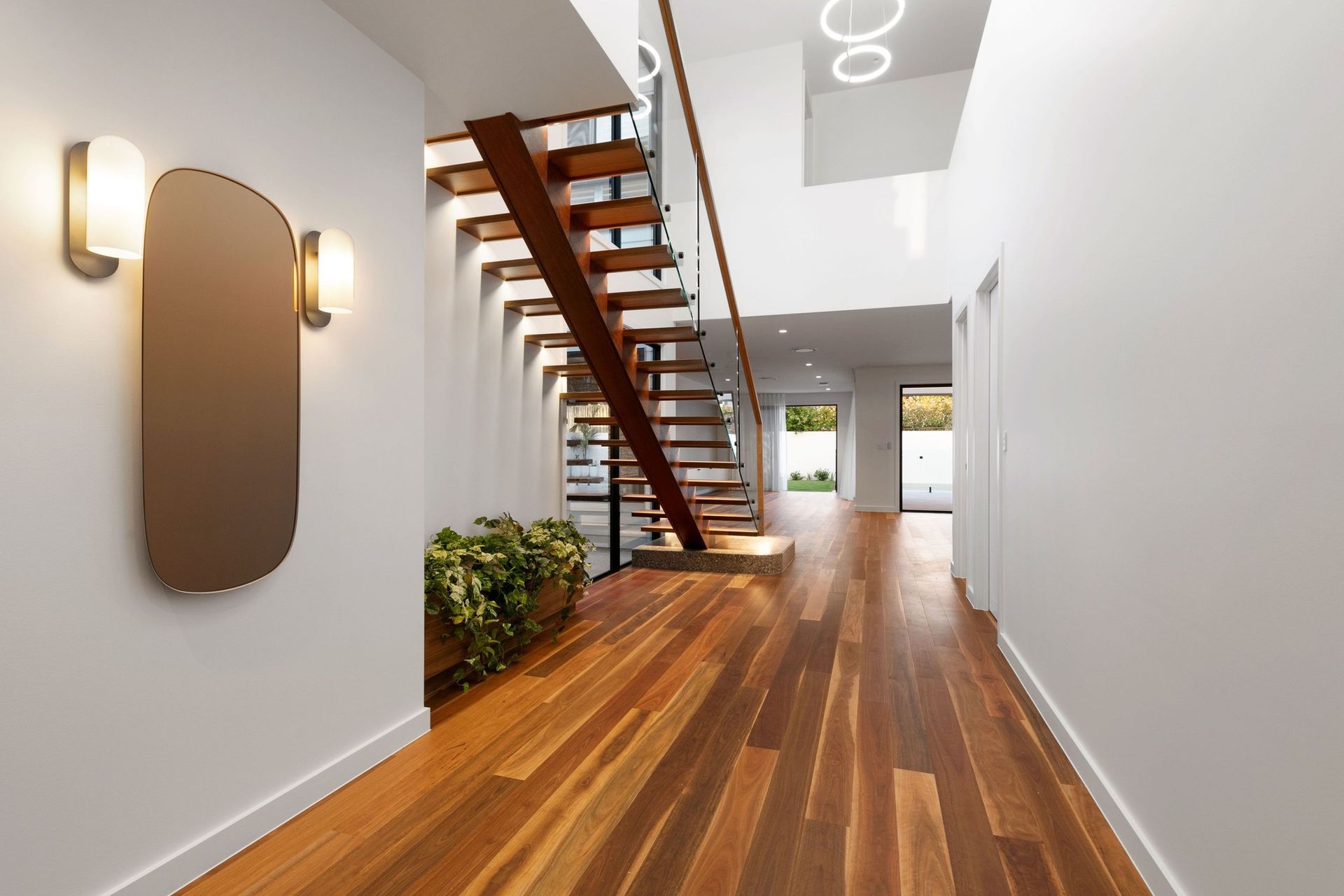 A floating spotted gum staircase and double-height void give the entry light and lift.
