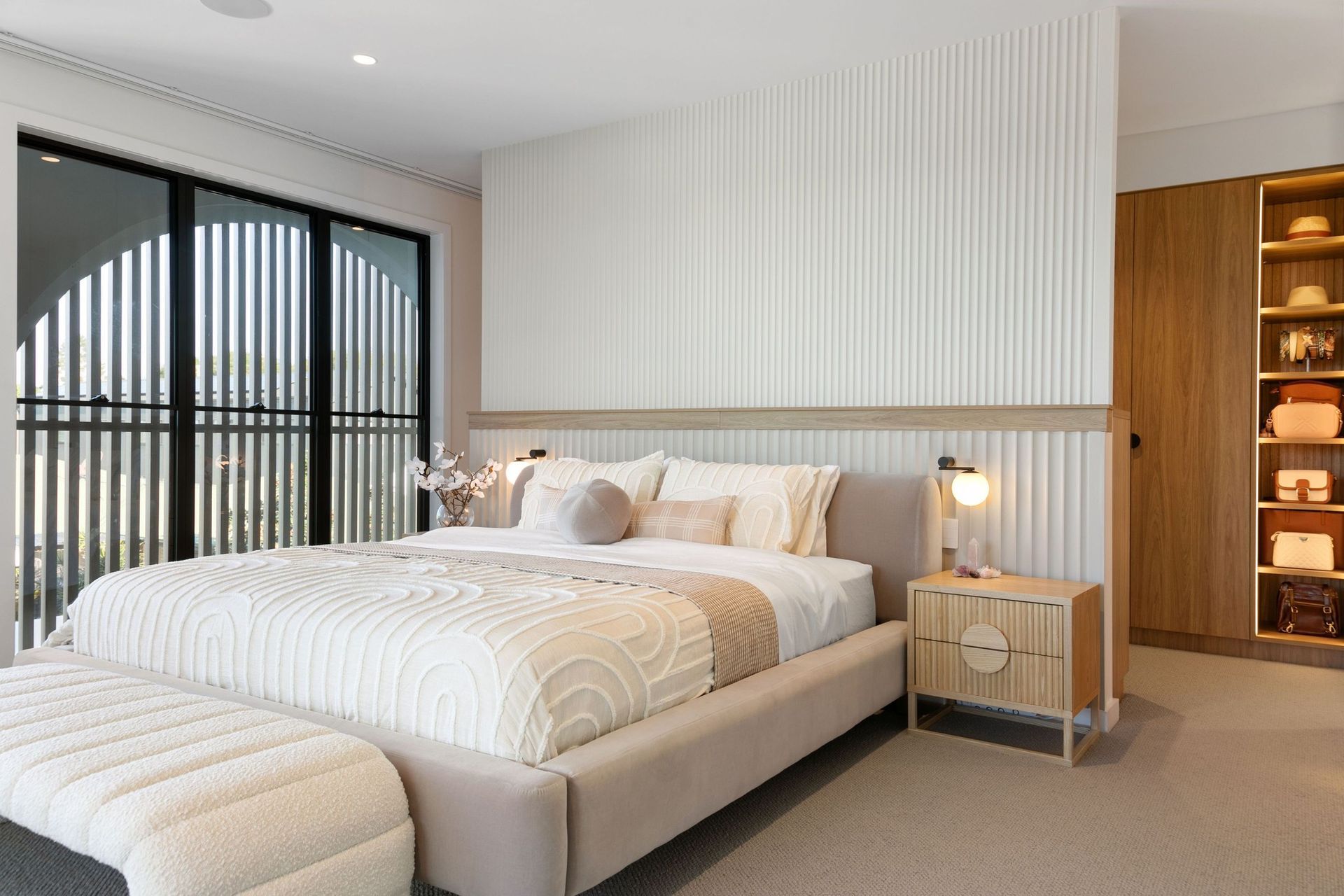 An arched window and full fluted wall give the main bedroom its calm.