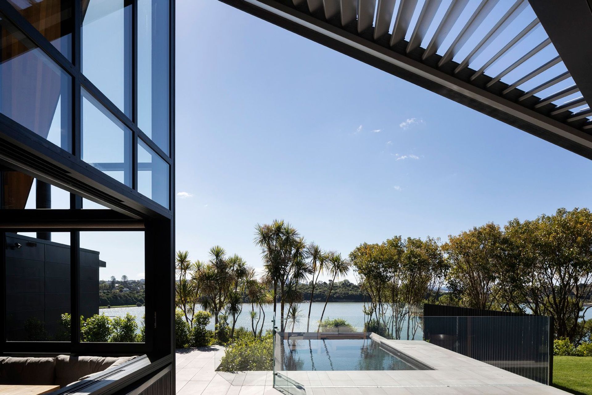 Operable louvres above the outdoor room allows morning sun to penetrate into the dining room while the view beyond the pool takes in the Orakei Basin.