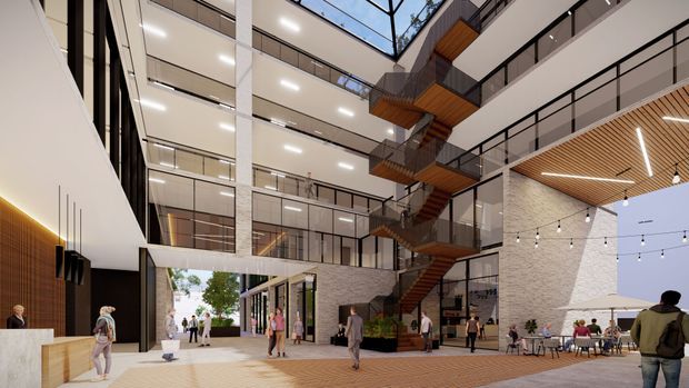 A spacious multi-storey contemporary commercial atrium or courtyard with extensive glass-fronted levels, open circulation galleries, and a prominent zigzag staircase with warm timber treads and soffits. Light brick and white structural finishes frame the space, while a timber slatted ceiling, linear lighting, café-style seating, planters, and pedestrians create an active public environment. The atrium is open to the sky and visually connects multiple floors.