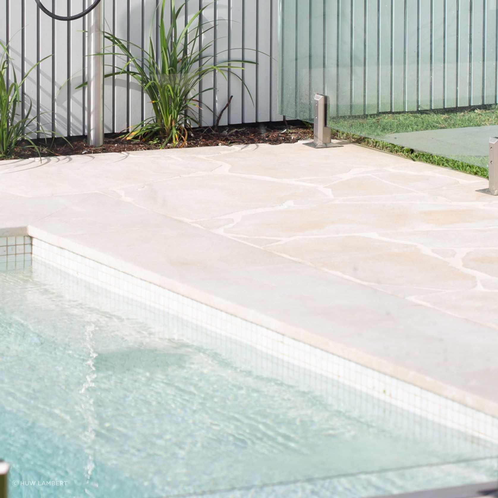Cathedral crazy paving limestone pool surround with outdoor shower at modern barn house in Randwick, Sydney