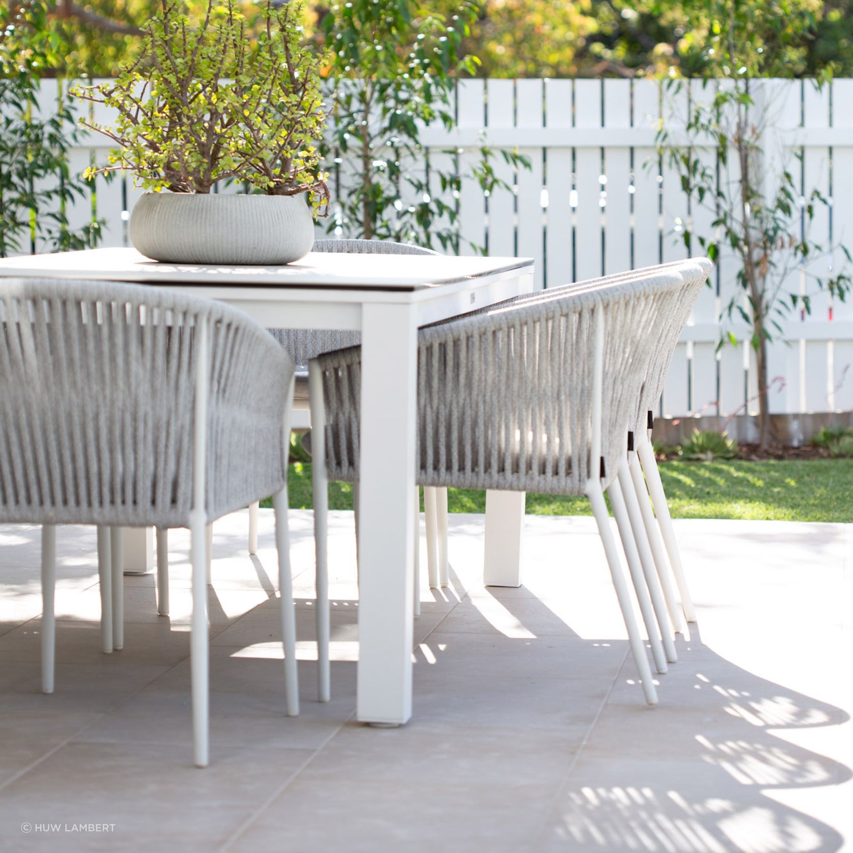 Lavarosa limestone alfresco outdoor terrace with white dining furniture and dappled sunlight