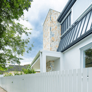 Exterior home facade featuring Summit natural stone wall cladding with white render and charcoal metal roofing.