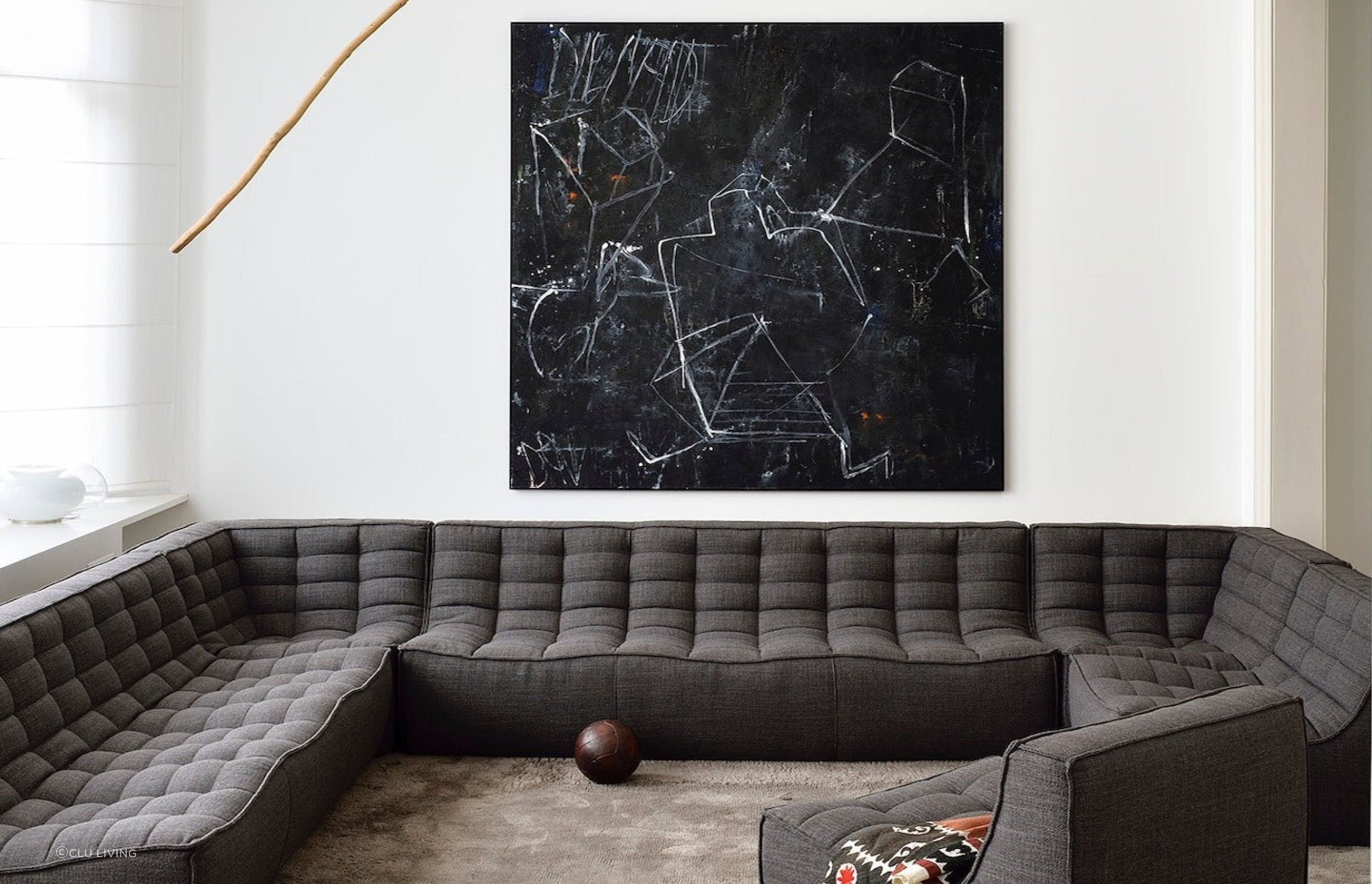 A clear white wall and distinct wall art provide a great backdrop to this dark grey corner sofa. Featured product: N701 Sofa Corner.