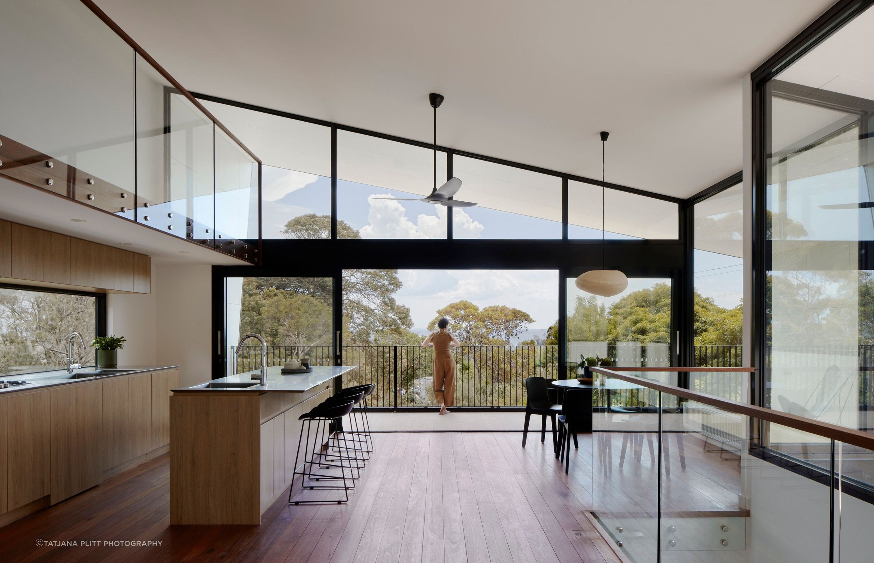 Floor-to-ceiling glazing captures the outlook across the bush landscape and out to the water.